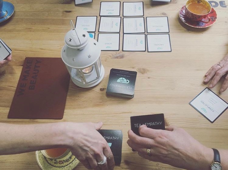 two hands hold cards while a spread is on the table
