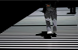 person in striped pants walks on striped cross-walk.